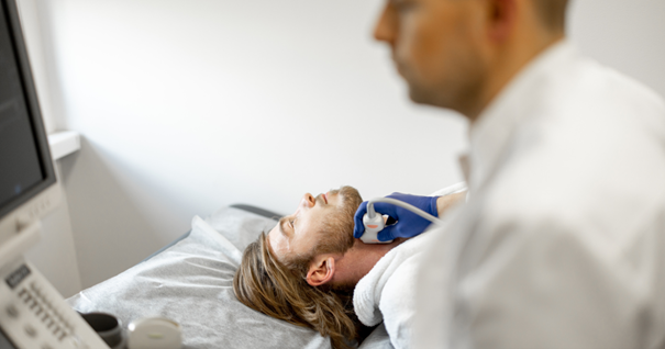 A healthcare professional performs an ultrasound examination on a patient's neck, focusing on the carotid artery. The patient lies on an examination table, while the professional uses a handheld ultrasound device to scan the neck artery.